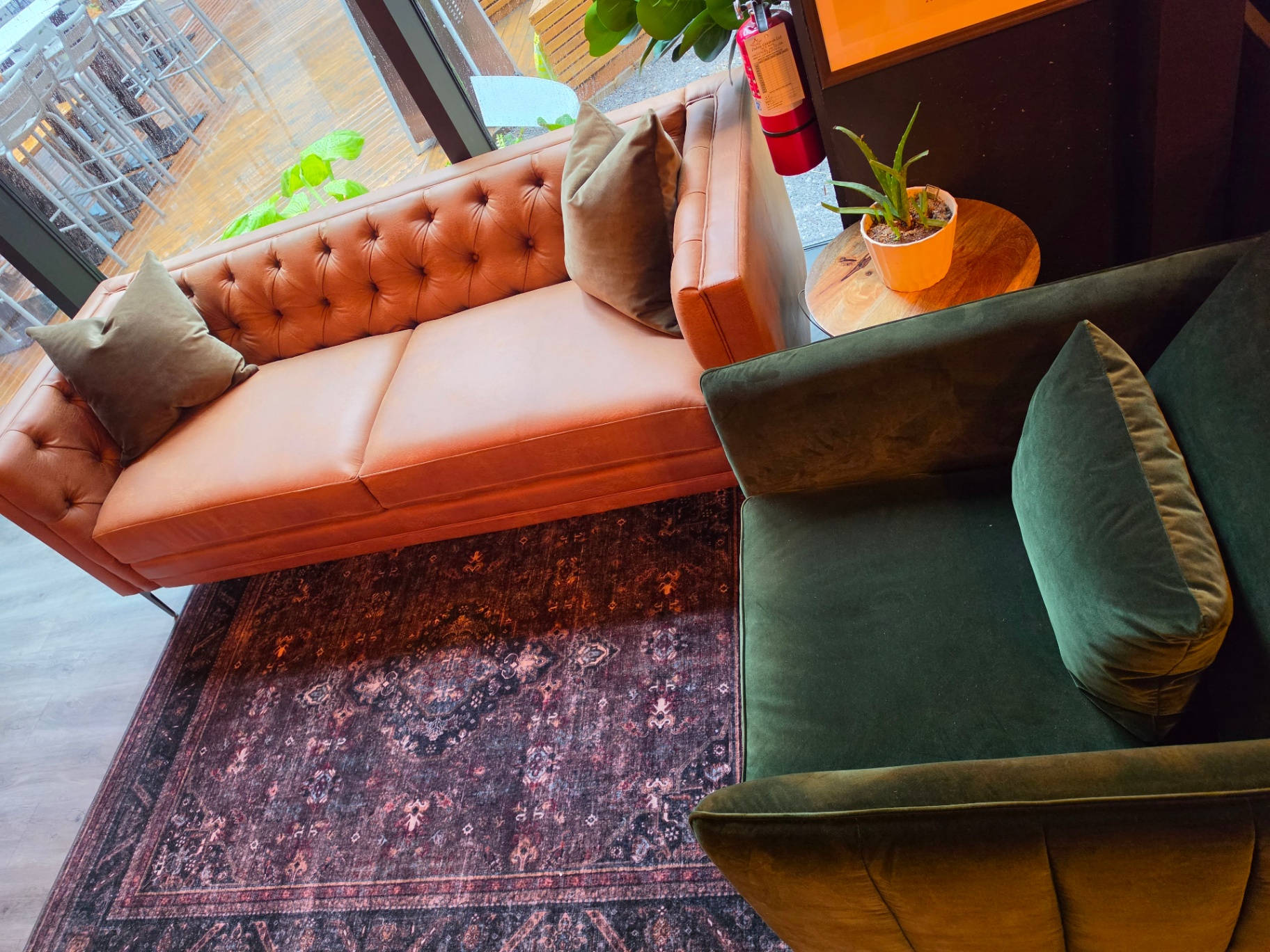 Tan leather chesterfield and emerald velvet lounge seating with vintage rug